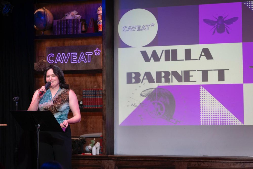 Willa hosting at Caveat with her name projected behind her