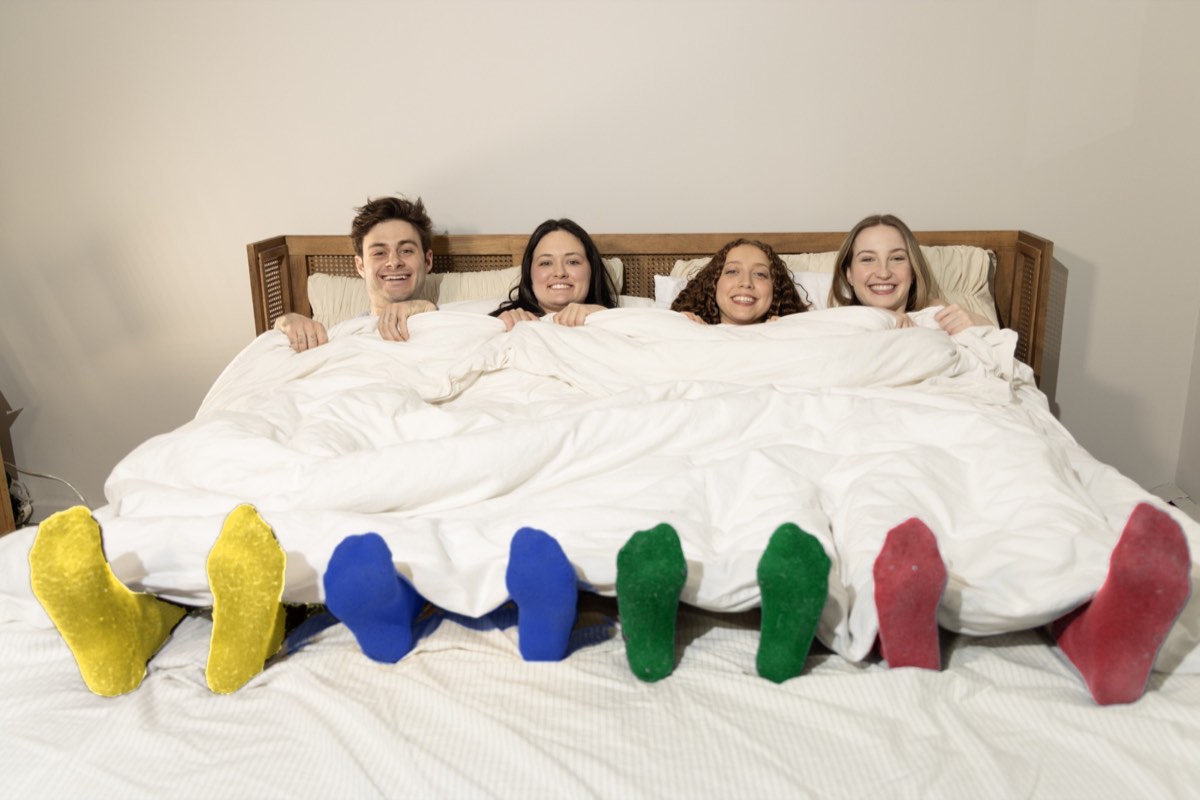 Skip Skip tucked into one giant bed, four pairs of colored socks sticking out
